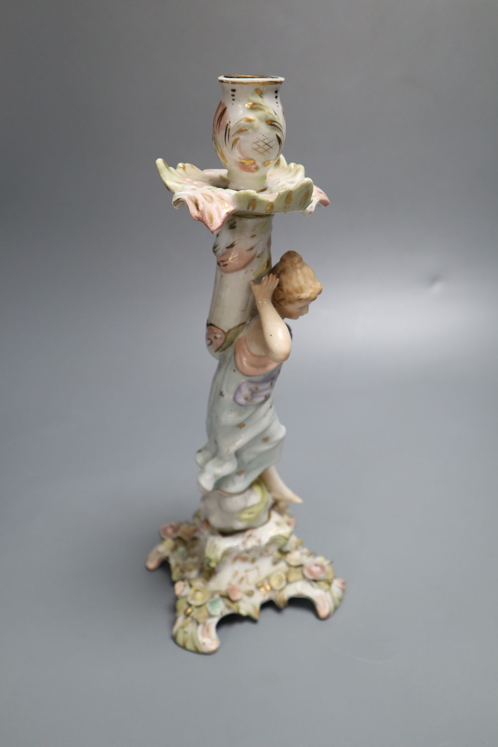 A German porcelain candlestick with lady and cherub, height 26.5cm (a.f.)